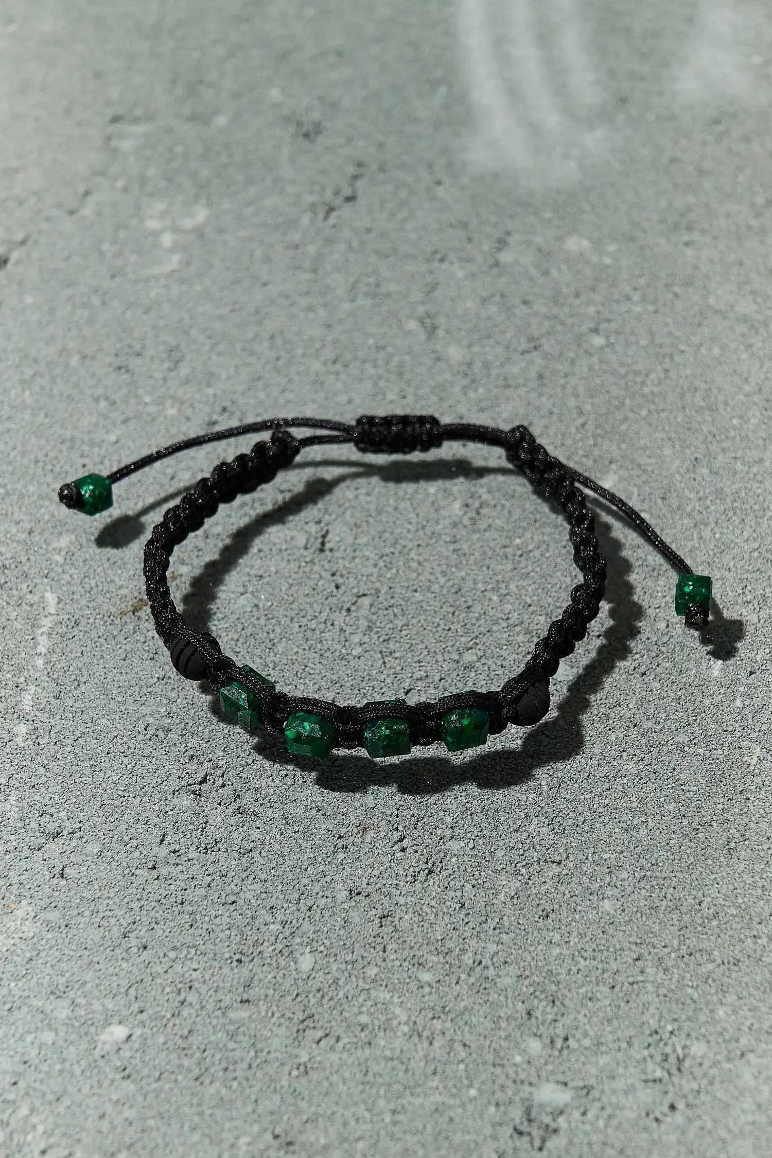 Primer plano de pulsera con esmeraldas cuadradas 100% naturales, mostrando el intenso verde característico de las esmeraldas colombianas y esferas de neopreno, diseño elegante y unisex 